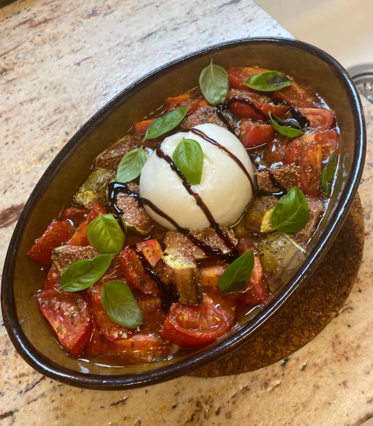Ofentomaten mit Feigen und Burrata, mit frischem Basilikum angerichtet